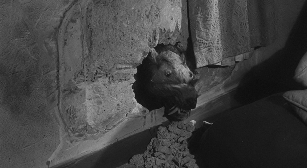 A dark, eerie scene showing a dog's head emerging from a hole in the wall, with debris scattered around its base and a curtain in the background.