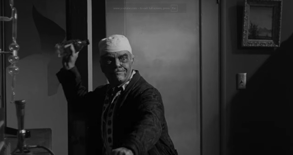 A man with a sinister expression is holding a glass bottle in one hand, preparing to throw it. He is wearing a white cap and dark clothing, standing in a dimly lit room with various objects in the background.