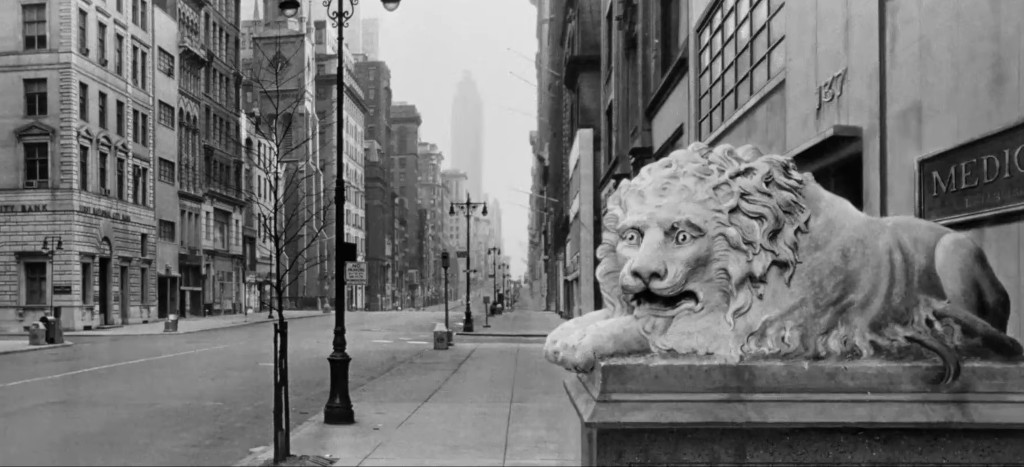A historic street scene featuring a prominent stone lion statue in the foreground, with empty city streets and tall buildings in the background, capturing a sense of urban architecture and early 20th-century design.
