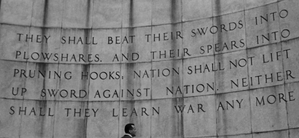 Close-up of a stone wall inscribed with the quote 'They shall beat their swords into plowshares. And their spears into pruning hooks; nation shall not lift up sword against nation. Neither shall they learn war any more.'